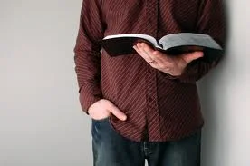 Hands holding open Bible showing ministry foundation on Scripture and the Word of God